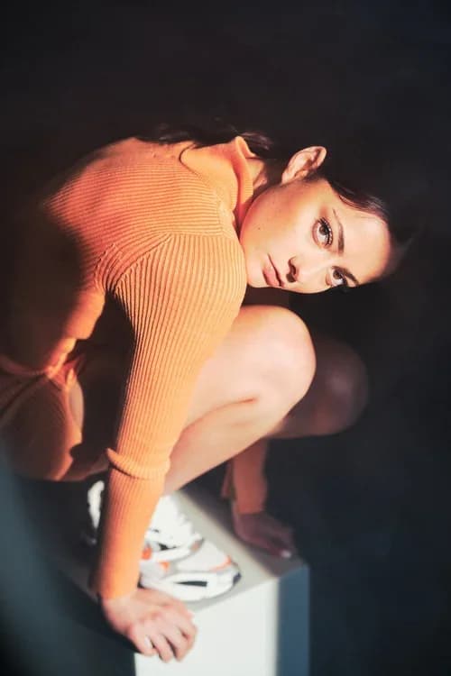 Lilith, in orange, sitting on a white block